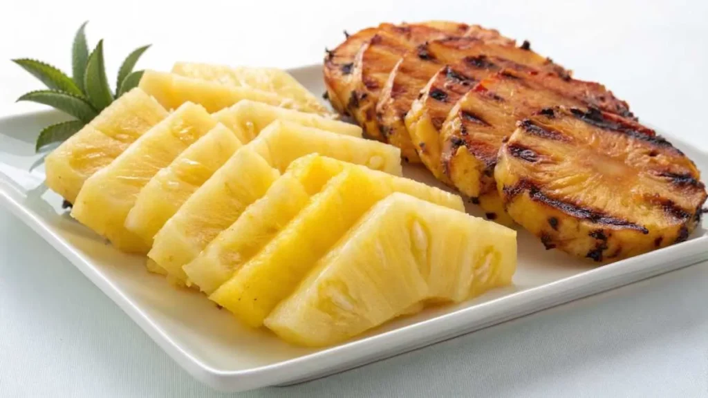 Fresh and grilled pineapple slices side by side on a white plate.