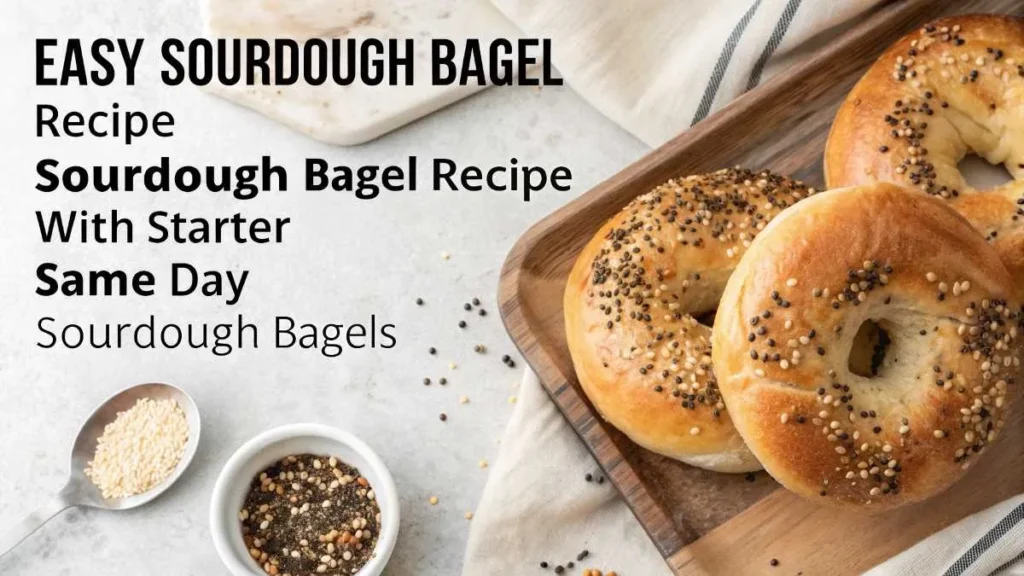 Freshly baked sourdough bagels on a wooden countertop, some topped with sesame seeds and others plain.